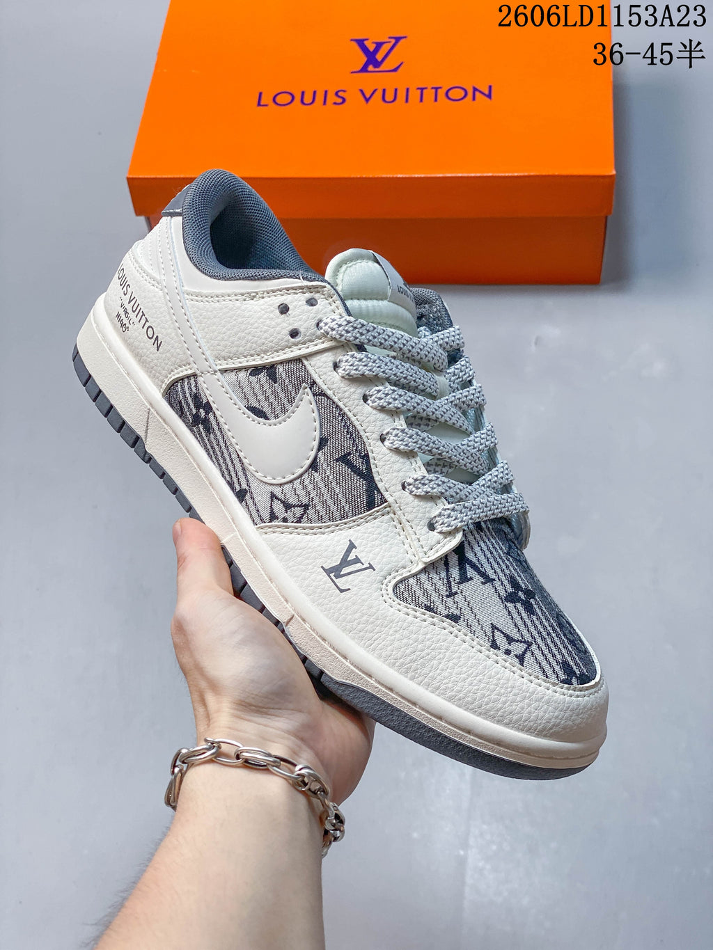 Close view of a white and gray patterned low-top sneaker with dark blue monogram-style print