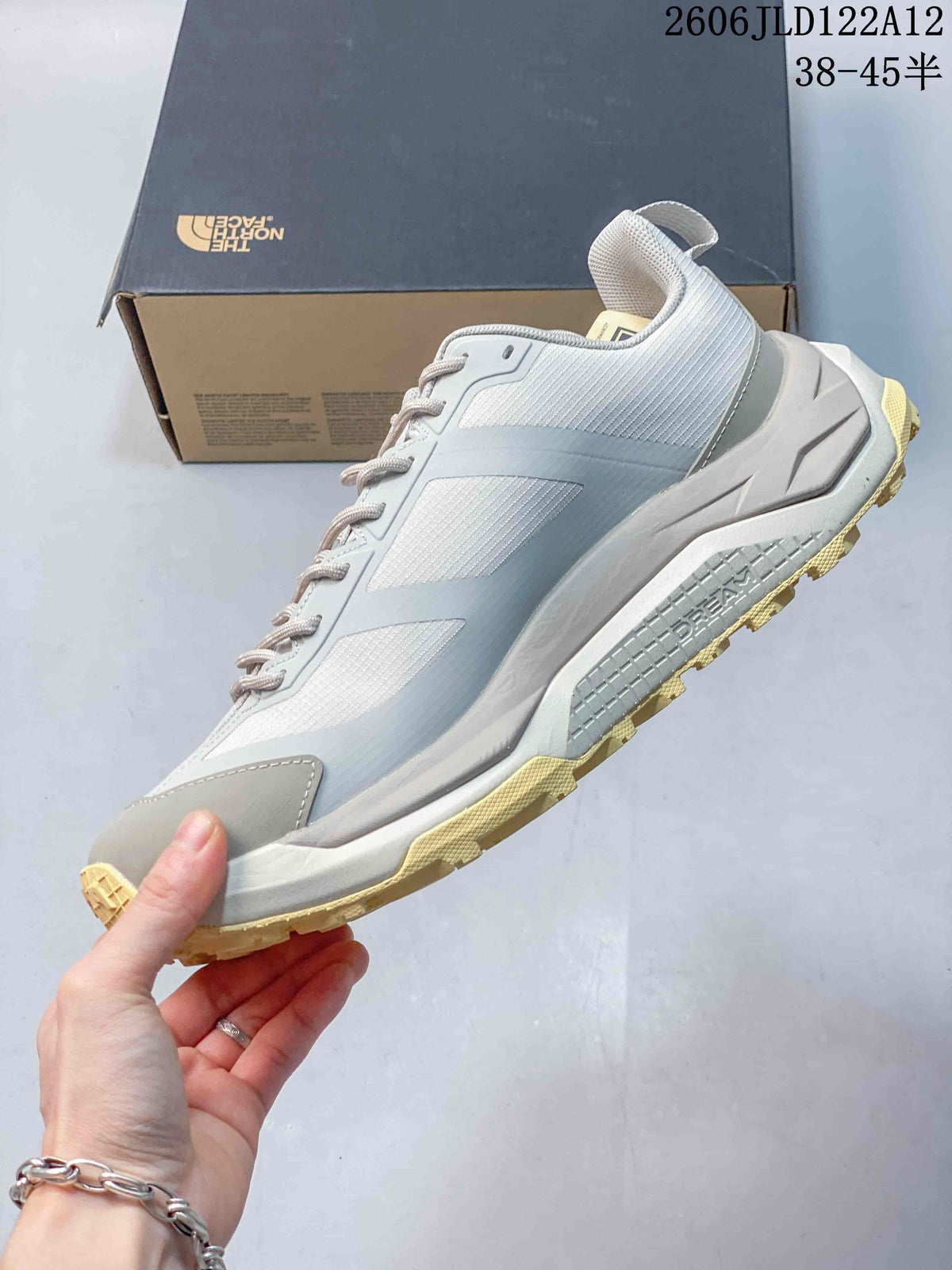 Side view of a light gray low-cut hiking shoe with lace-up closure and pale yellow tread.