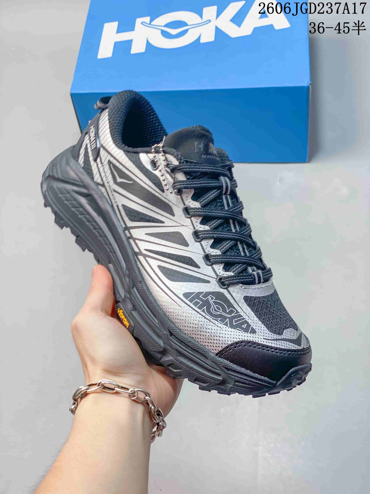 Angled side view of a silver-grey HOKA trail shoe with a rugged outsole