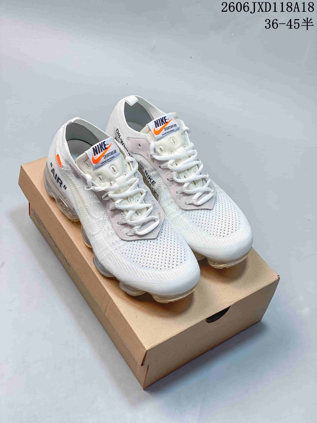 Pair of white Nike Air VaporMax sneakers with gray lace panels and clear air-cushion soles, shown on a box