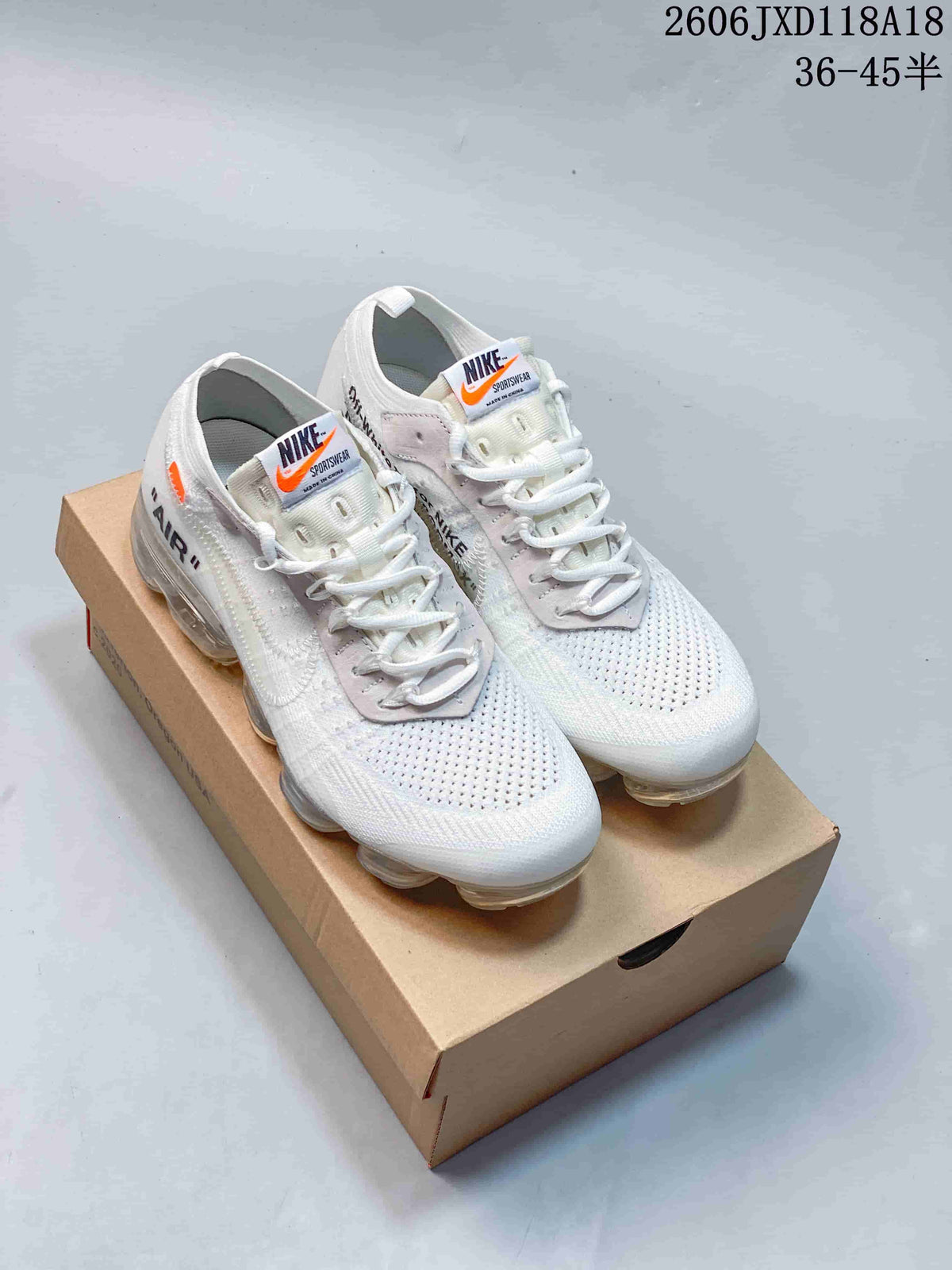 Pair of white Nike Air VaporMax sneakers with gray lace panels and clear air-cushion soles, shown on a box