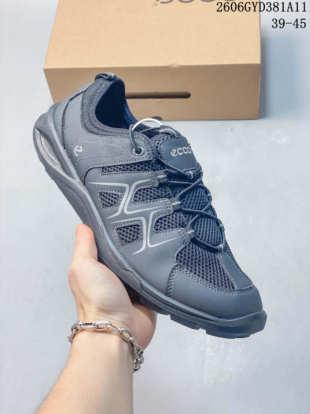 Angled side view of a gray sneaker with patterned overlays and elasticated laces.