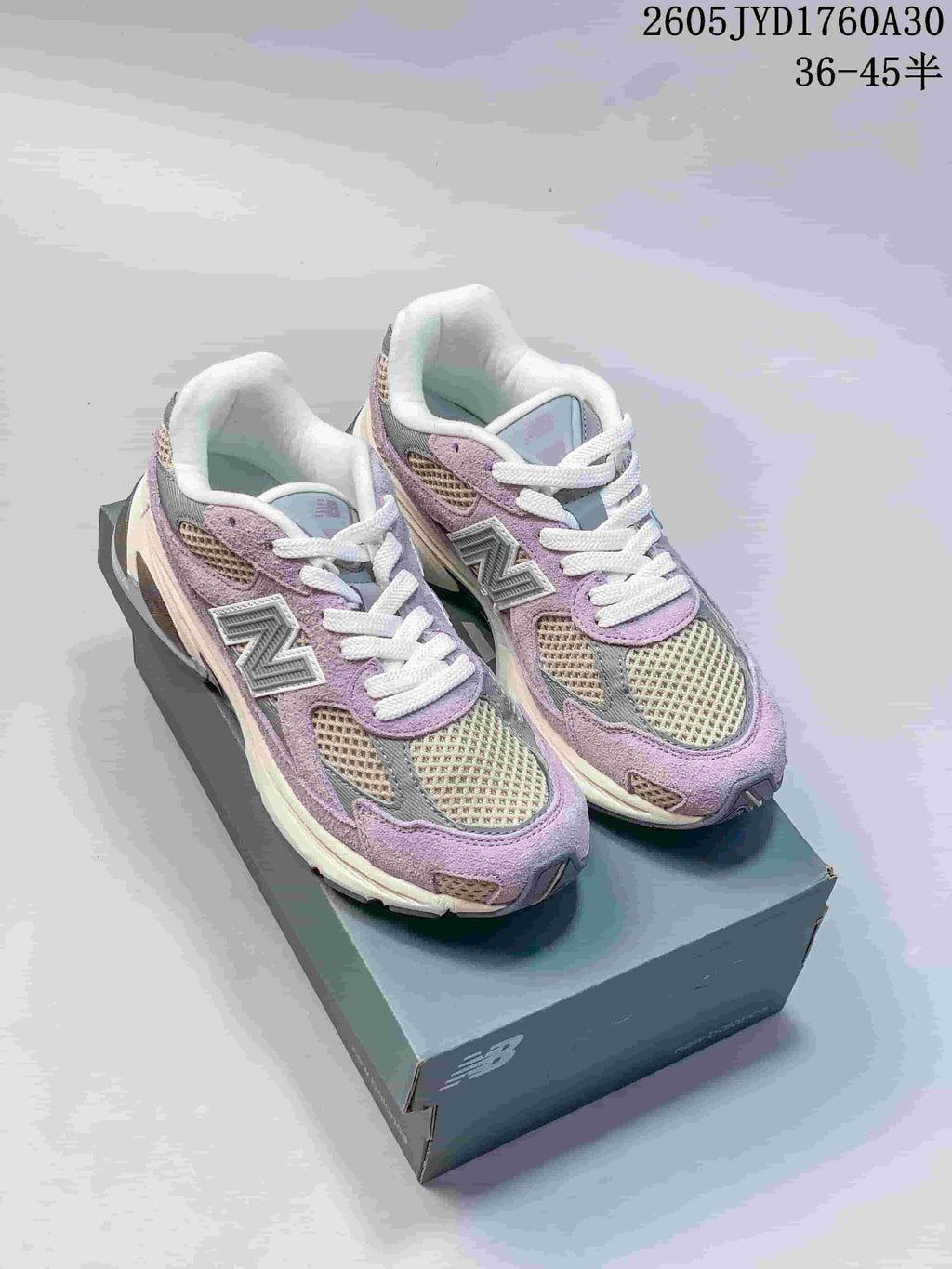 Pair of lavender, grey, and cream New Balance 2010 sneakers on a shoebox.