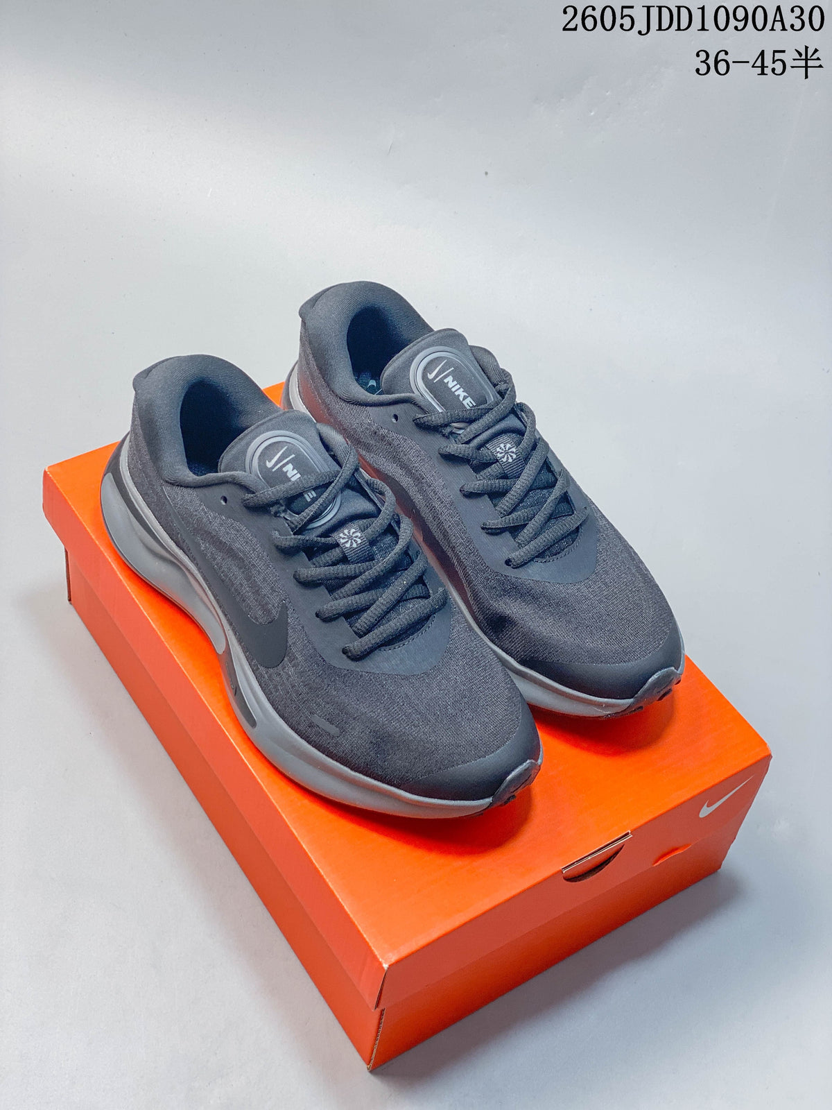 Pair of dark gray Nike Journey Run running shoes displayed on an orange shoebox.