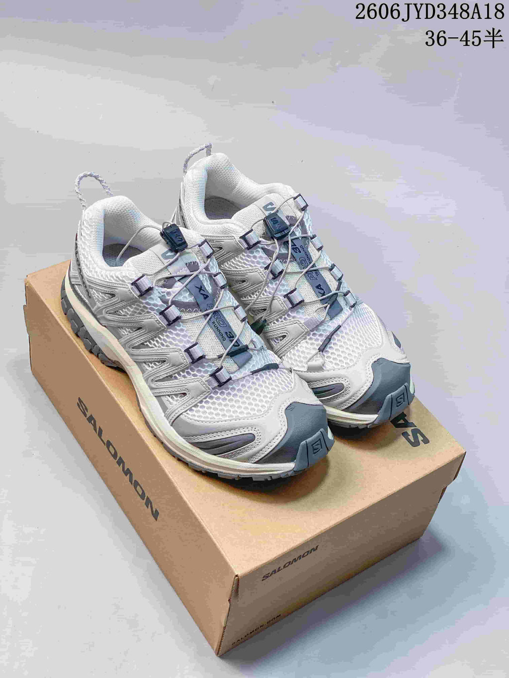 White and gray Salomon trail running shoes displayed on a branded shoe box.