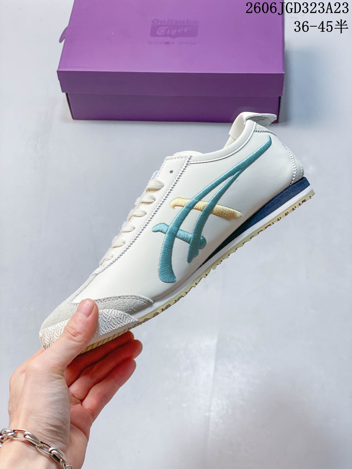Side profile showing teal-green stripes and gold accents on an ivory Mexico 66 NM sneaker