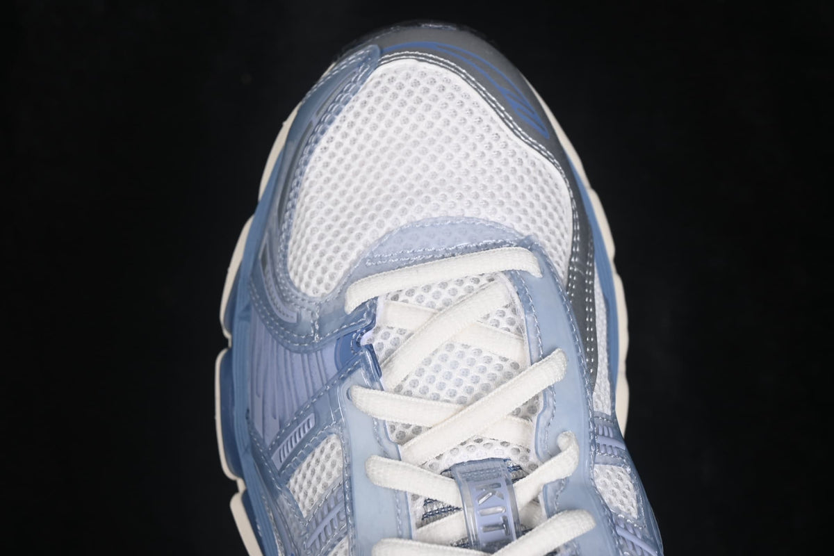 Close-up of the cream and light blue ASICS sneaker showing the mesh toe box, white laces, and layered blue overlays.