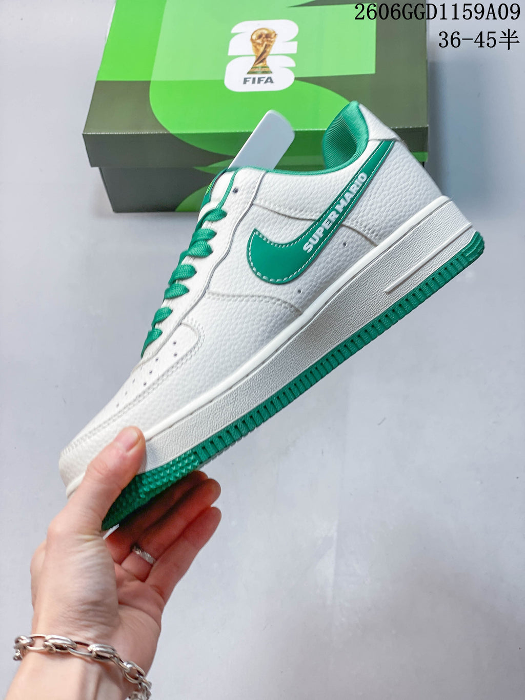 Side view of a white low-top sneaker with green Swoosh and Super Mario lettering