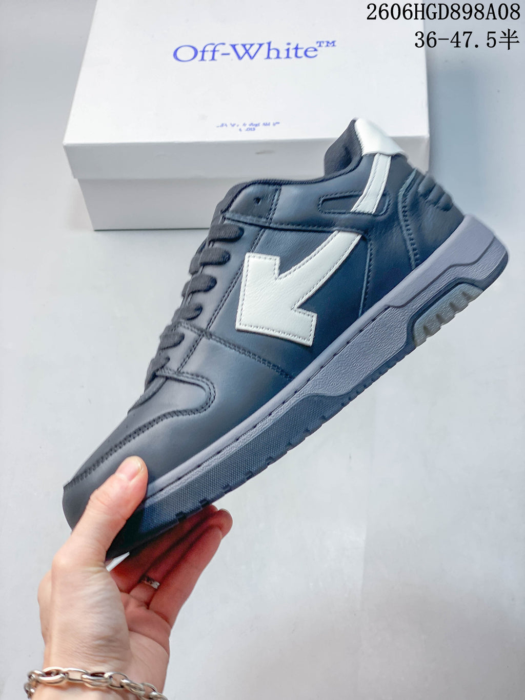 Side view of a charcoal-gray sneaker with a white arrow-shaped detail