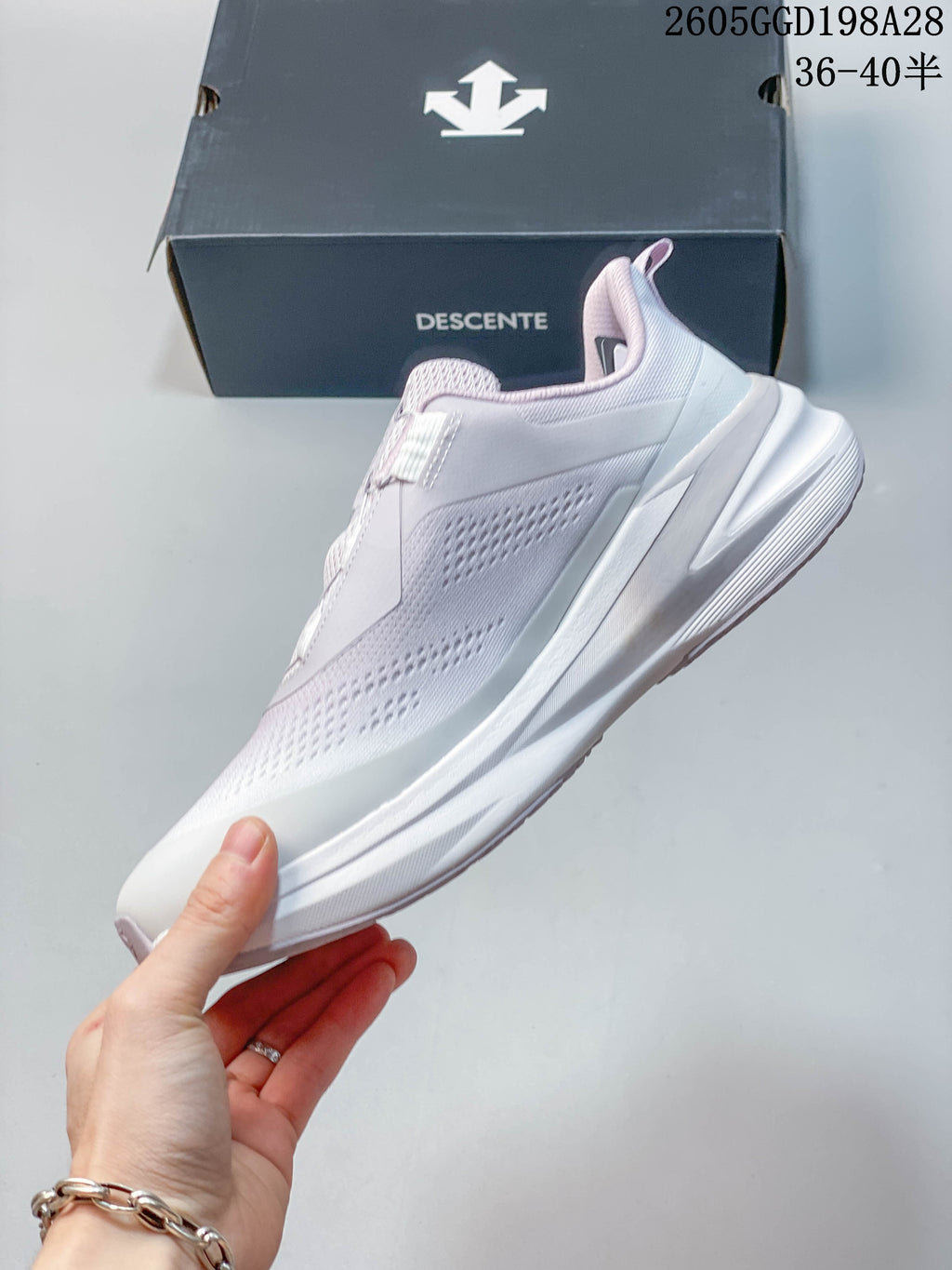 Side profile of a white and pale lavender DESCENTE running shoe.