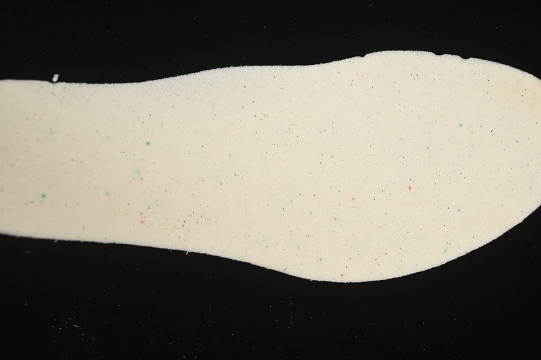 Light-colored shoe insole shown against a black background