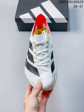 Top view of the white lace-up running shoe showing black stripes, red collar lining, and a yellow-red tongue detail.