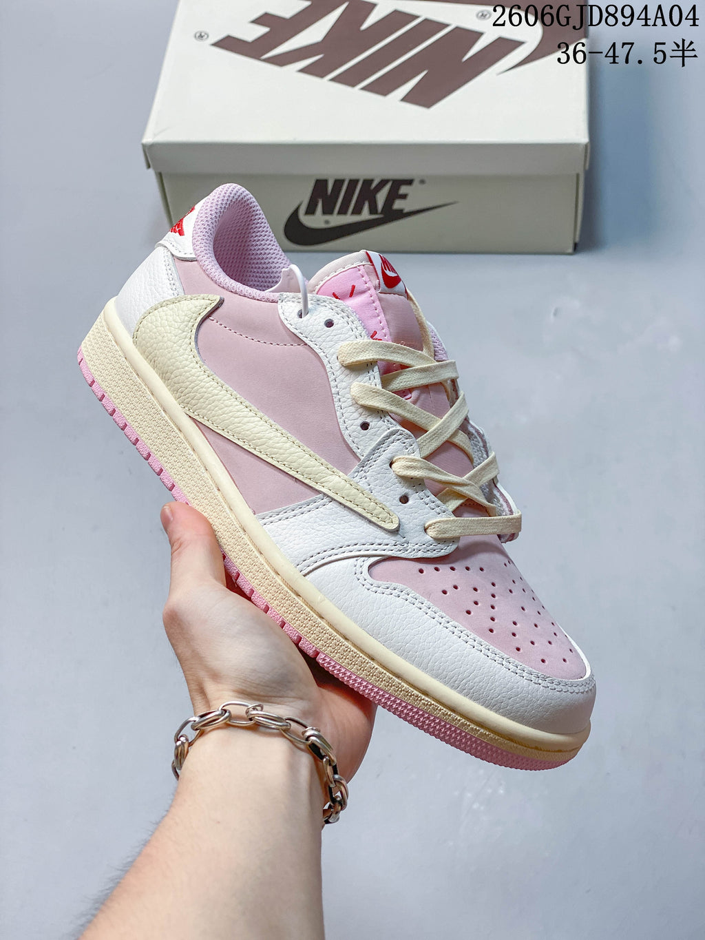 Side view of a pink and white low-top sneaker with a cream-colored Swoosh