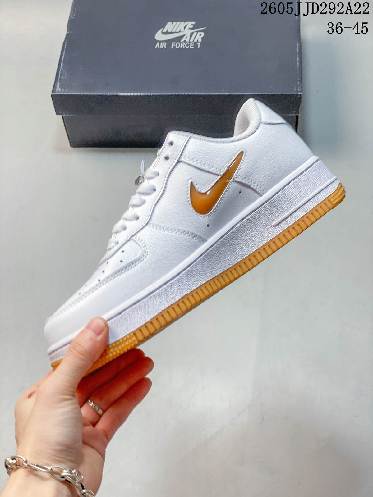 Side view showing the white layered upper, orange-gold Swoosh, and orange outsole
