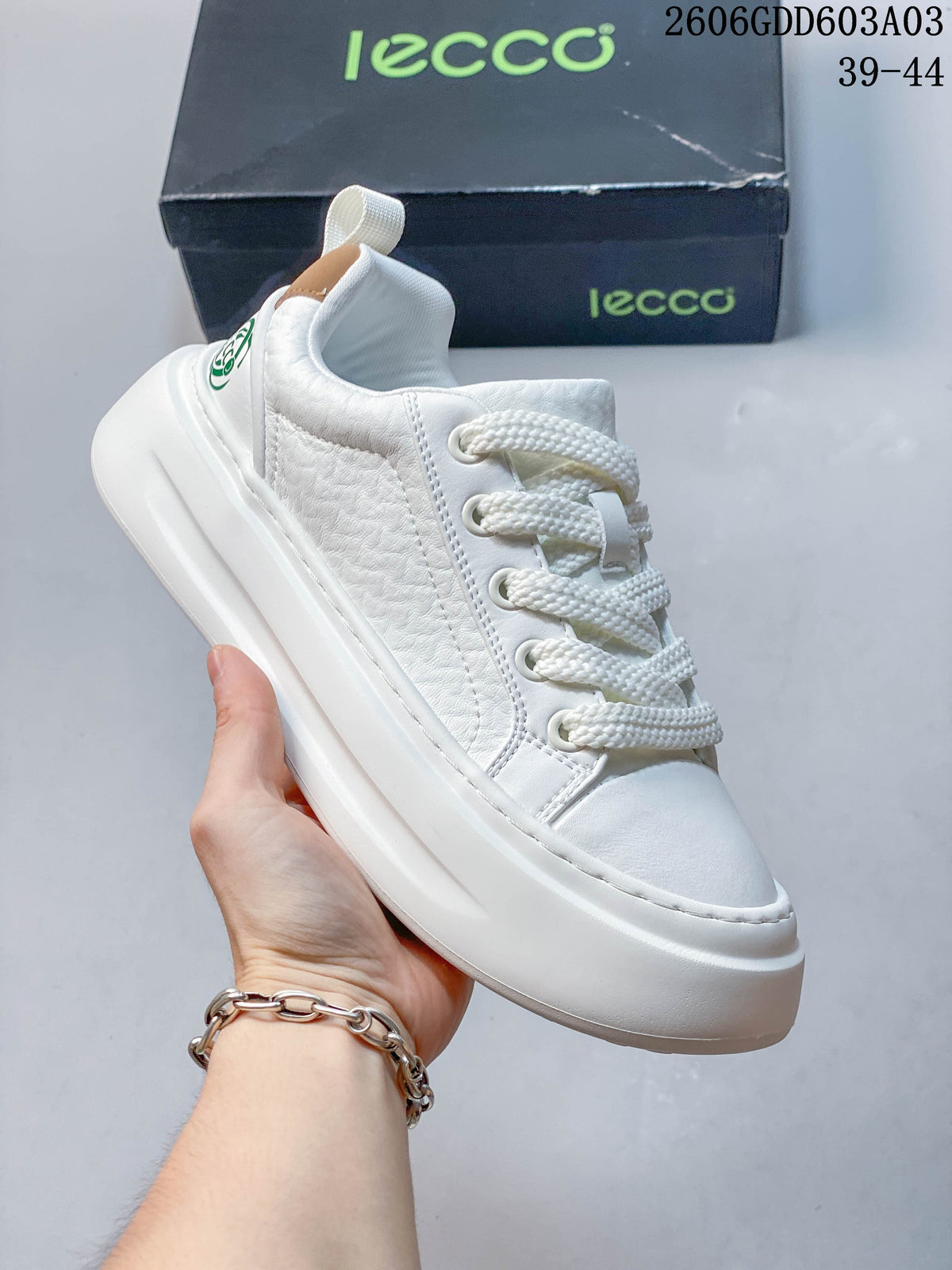 Angled side view of the white sneaker with textured panels, thick sole and heel pull tab; image overlay states sizes 39–44.