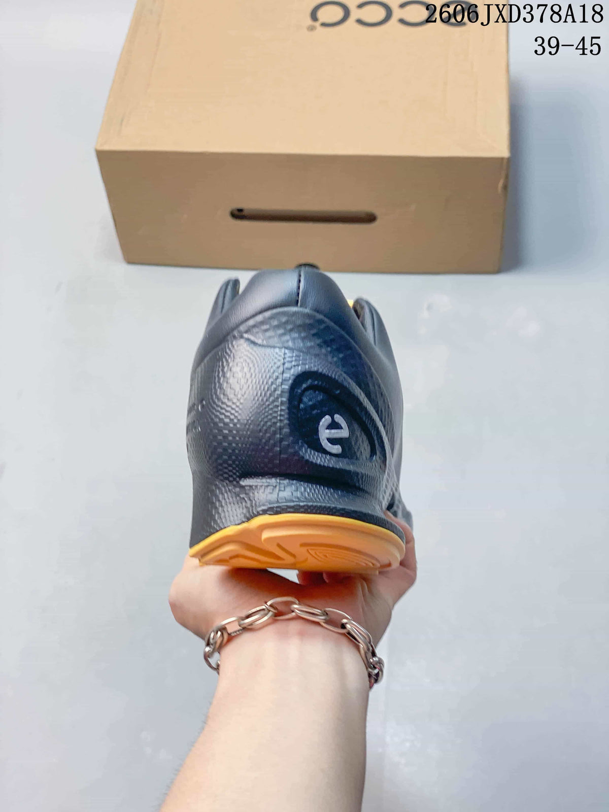 Rear view of a black ECCO BIOM sneaker with an orange outsole accent.