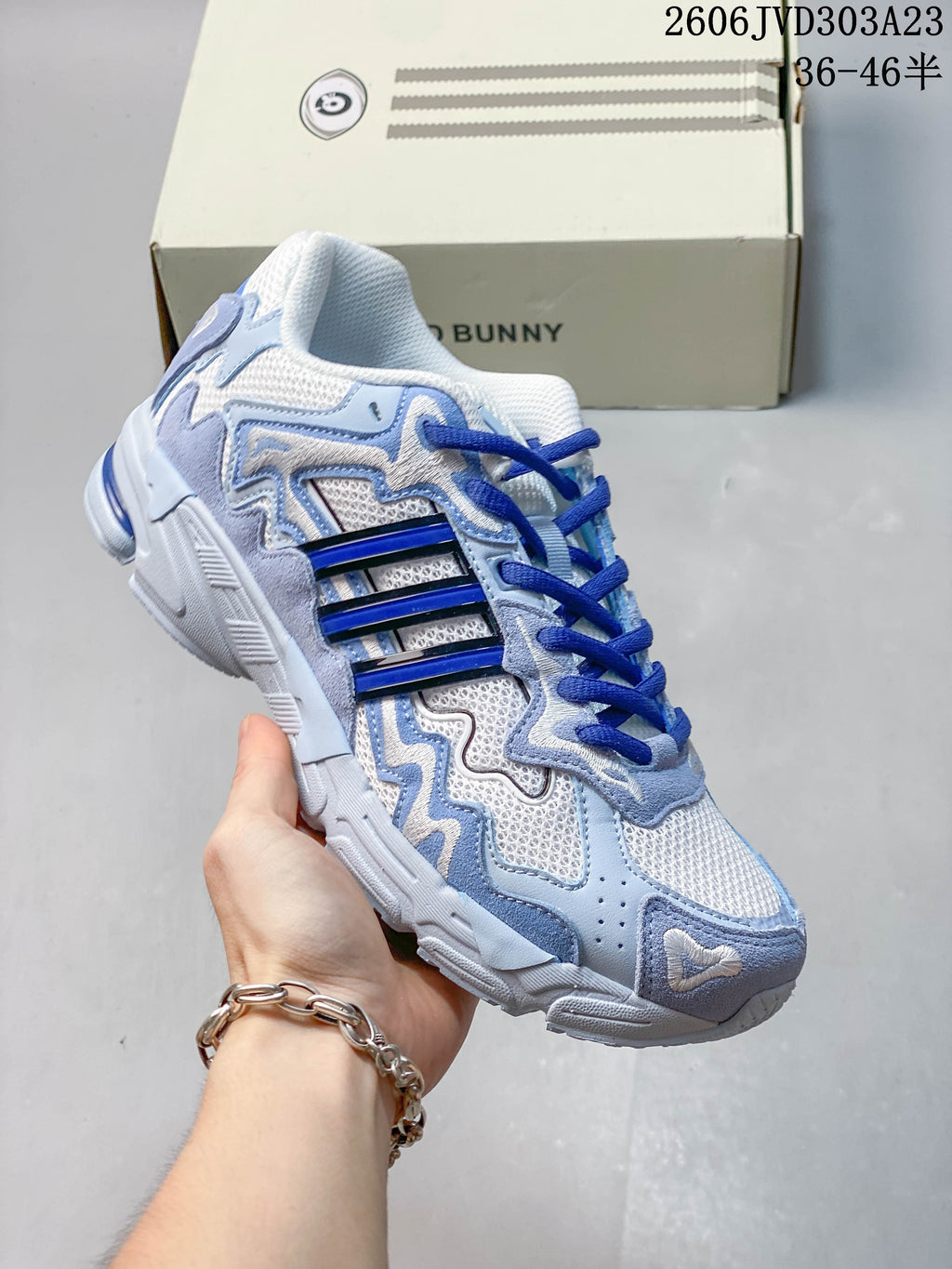 Angled side view of the white and light-blue sneaker with royal-blue accents
