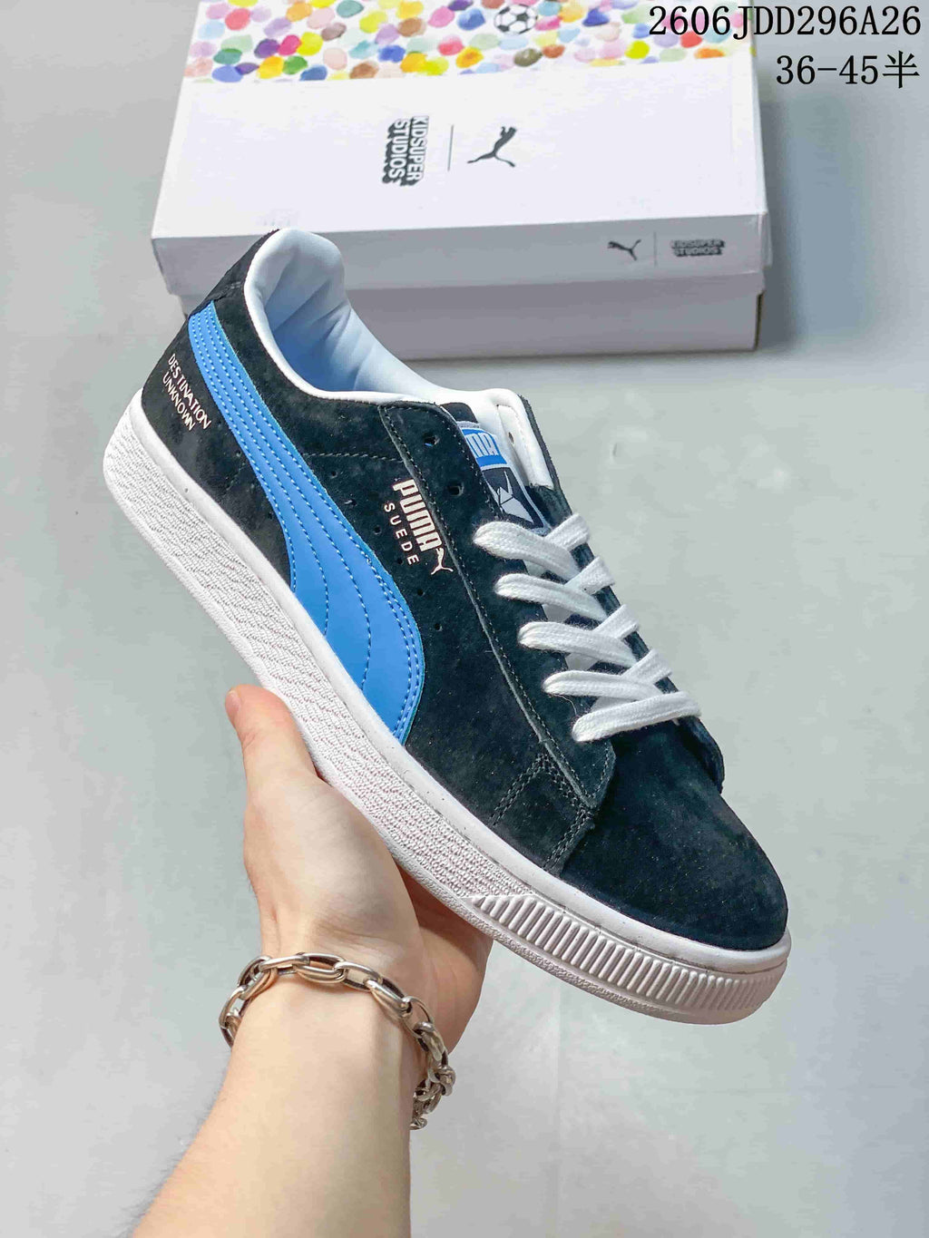Angled side view of a dark PUMA Suede sneaker with blue stripe, white laces, and white sole.