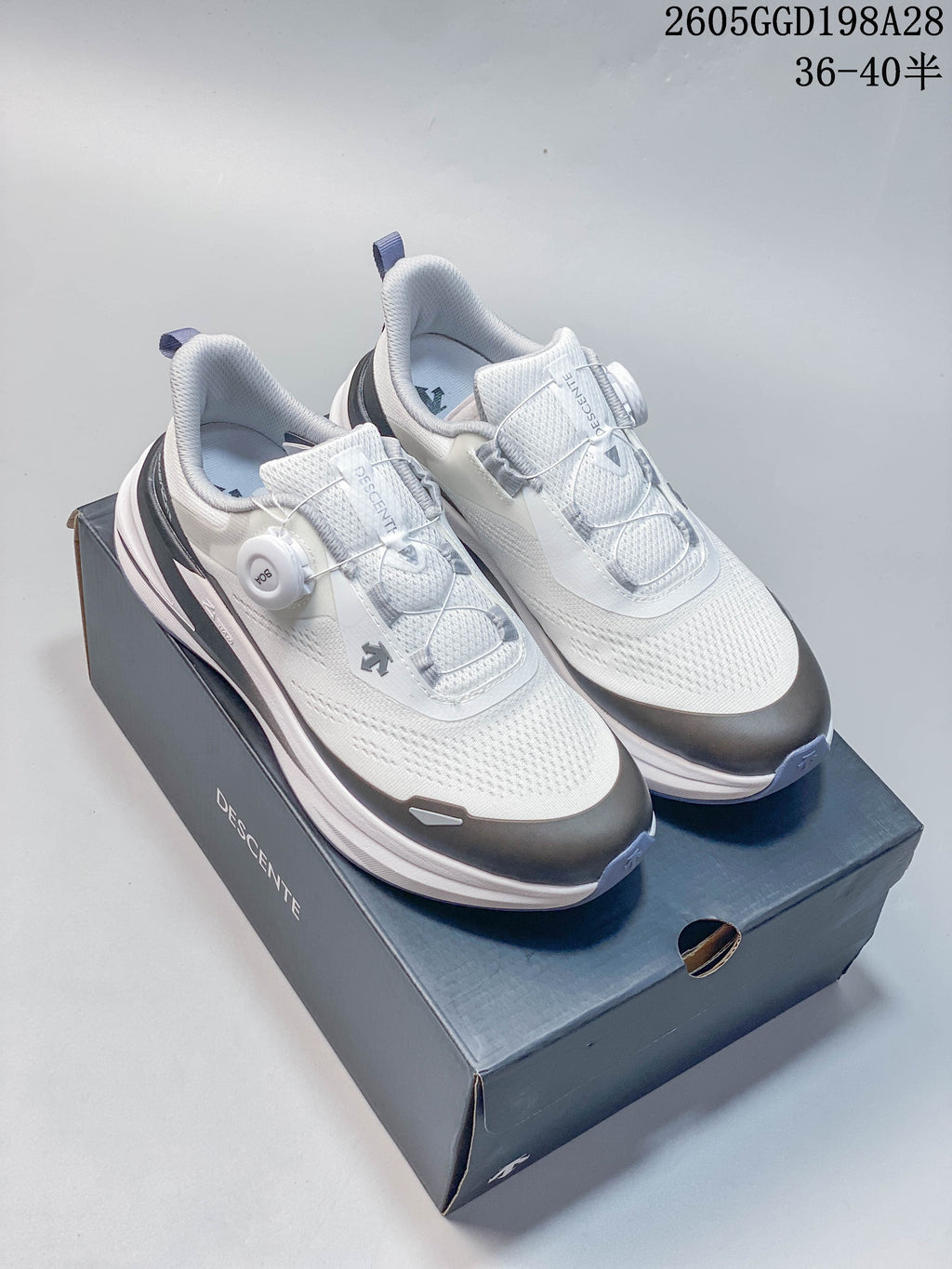 White Descente BOA running shoes with a dial closure on a Descente box; image overlay shows code 2605GGD198A28 and size range 36–40.5.
