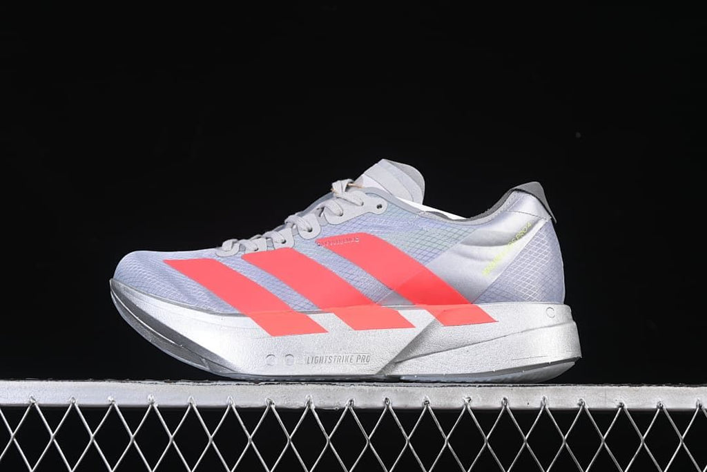 Side view of gray Adidas Adizero Adios Pro 4 running shoe with coral stripes