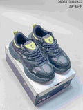 Pair of charcoal-gray FILA sneakers with lime accents shown on a shoebox
