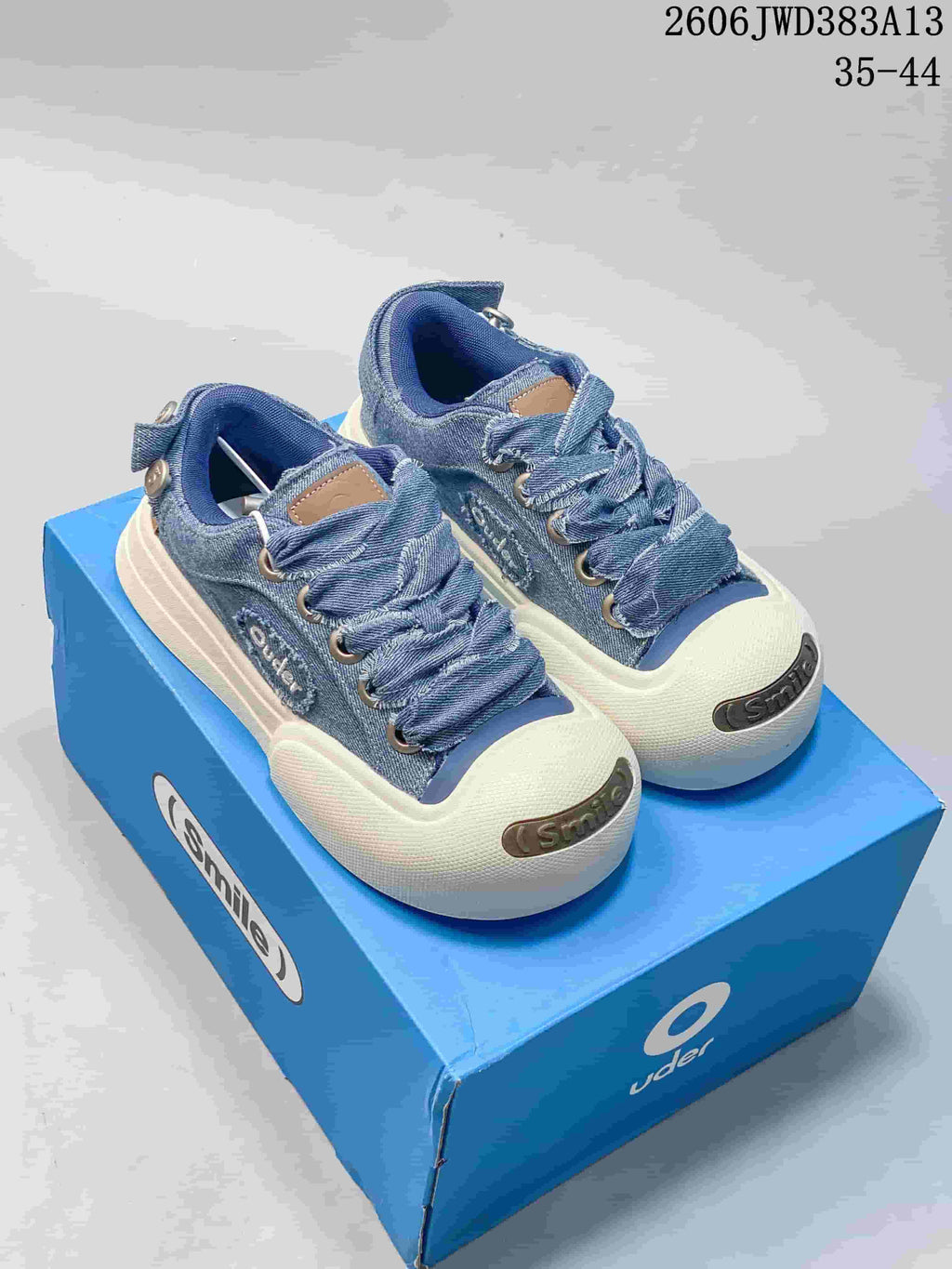 Pair of blue denim Ocai Smile low-top sneakers with oversized laces and white toe bumpers.