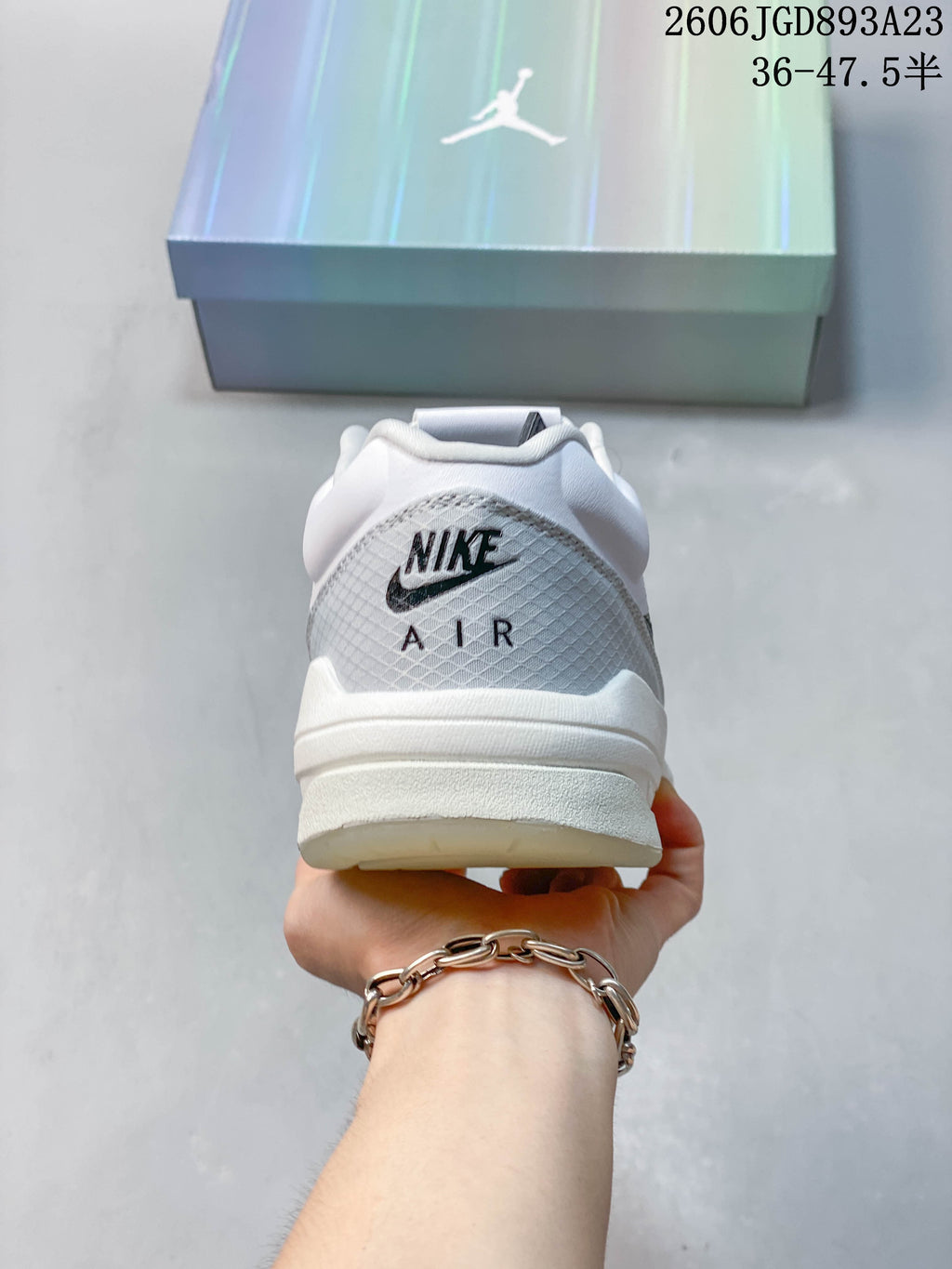 Rear view of a white and grey Jordan Stadium 90 sneaker with heel branding.