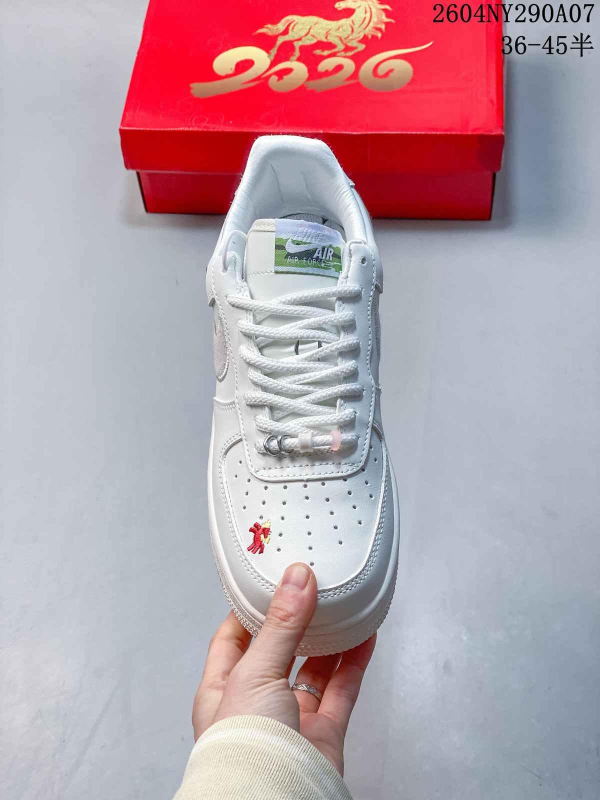 Top view of a white sneaker showing perforations, white laces, a green tongue label and a small embroidered horse.