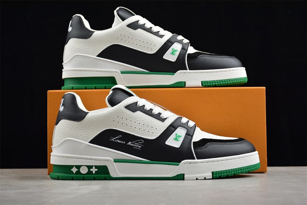 Two white, black and green LV Trainer sneakers displayed in front of a box.