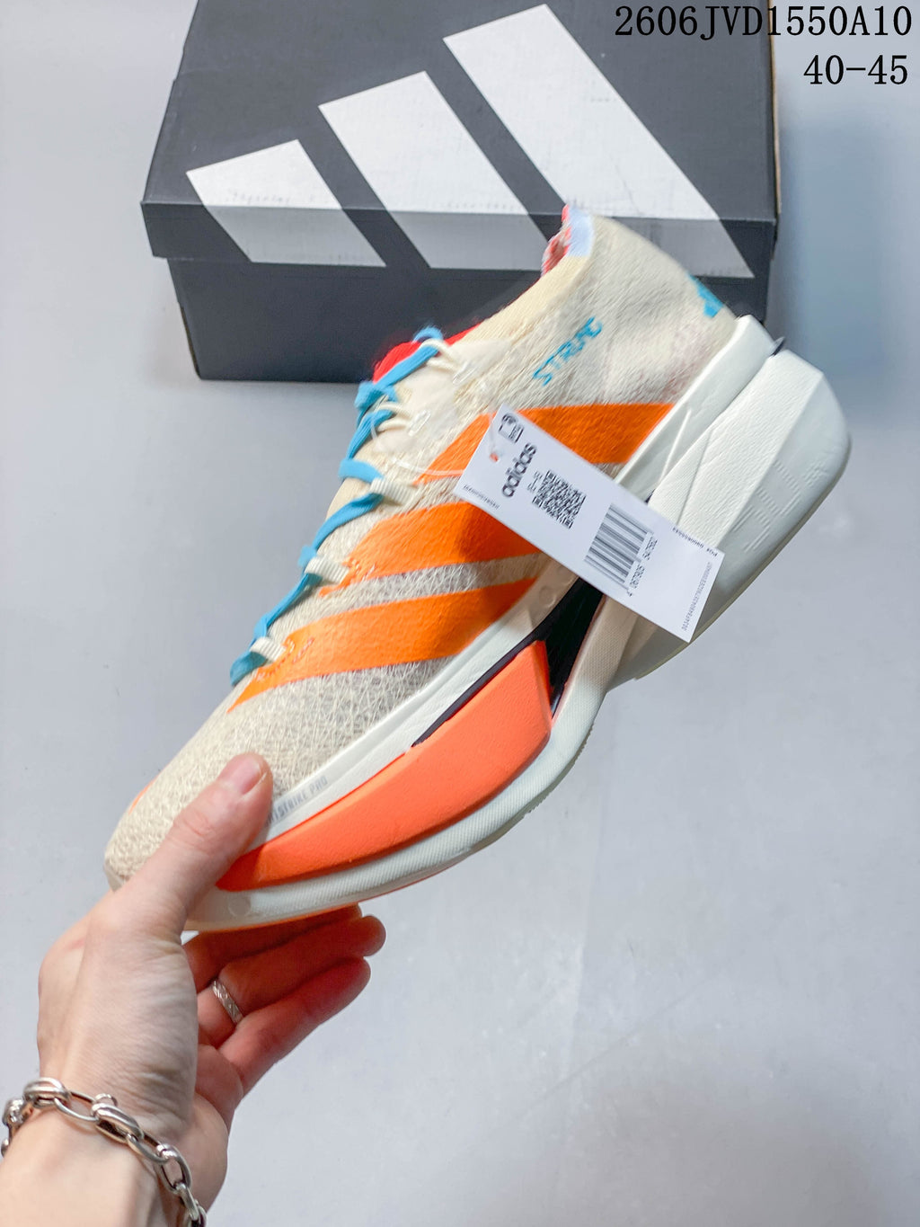 Side view of the cream and orange Adidas running shoe with blue laces.