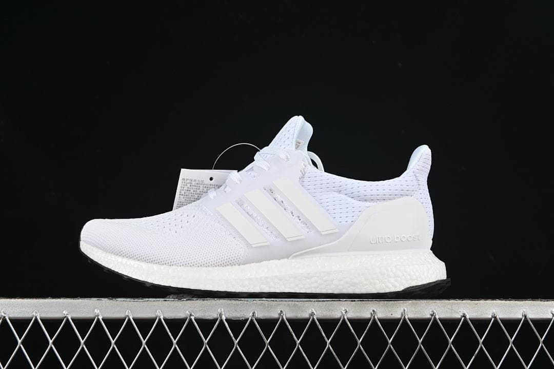 Side profile of white Adidas UltraBoost 1.0 sneakers against a dark background.