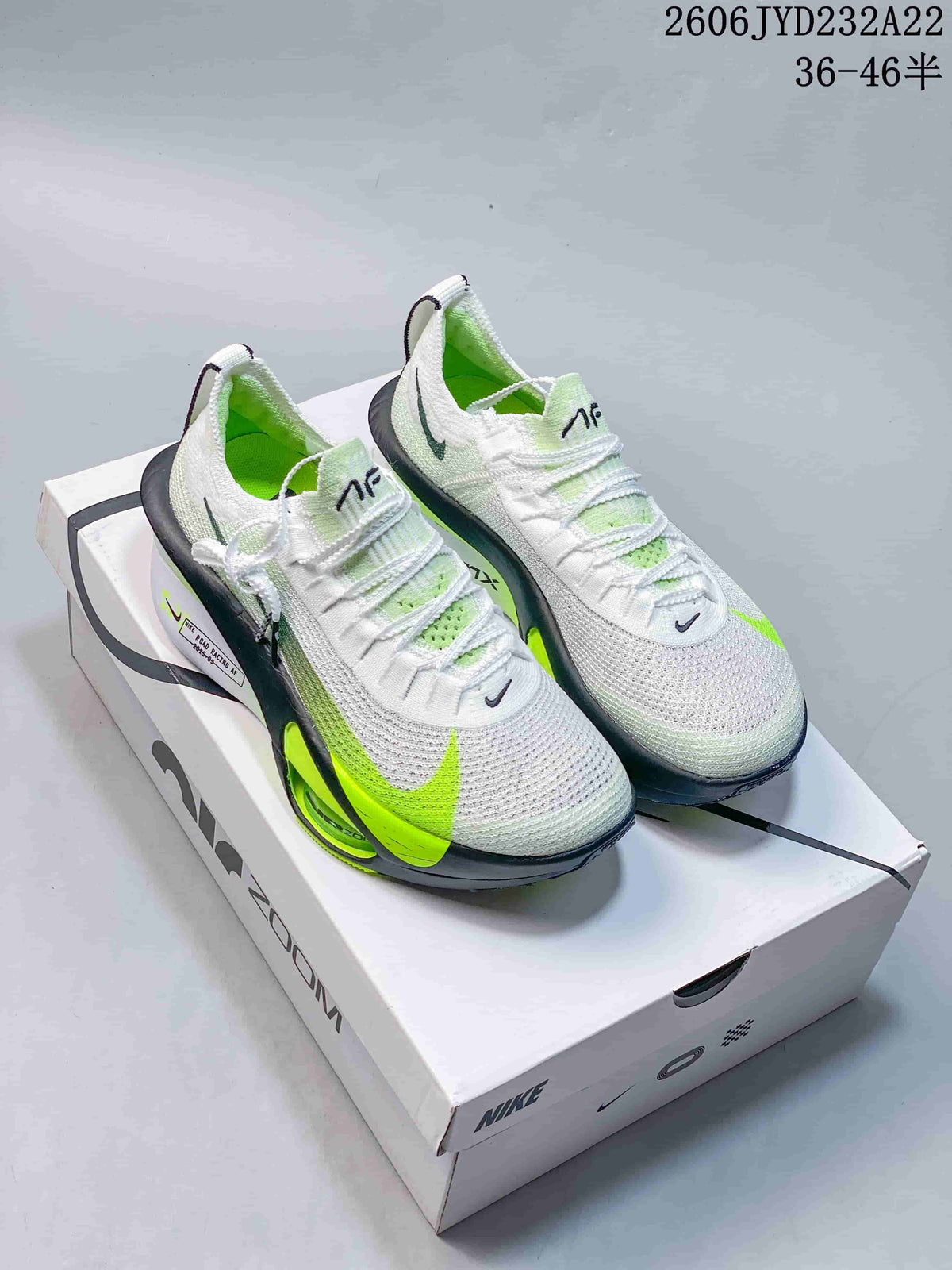 Pair of white Nike Air Zoom Alphafly Next% 3 running shoes with bright green accents on a Nike box