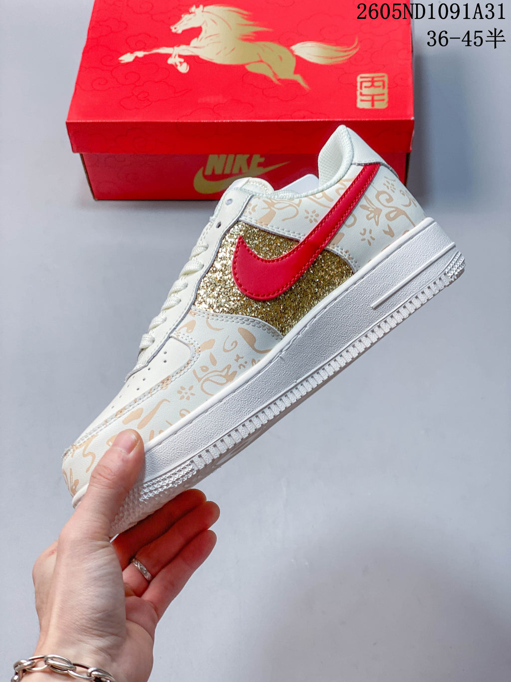Side view of the sneaker with a red Swoosh, gold glitter panel and tan decorative print.