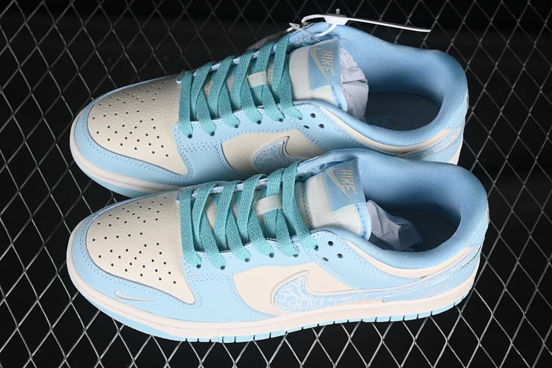 Top view of a pair of pale blue and off-white Nike SB Dunk Low sneakers with teal laces