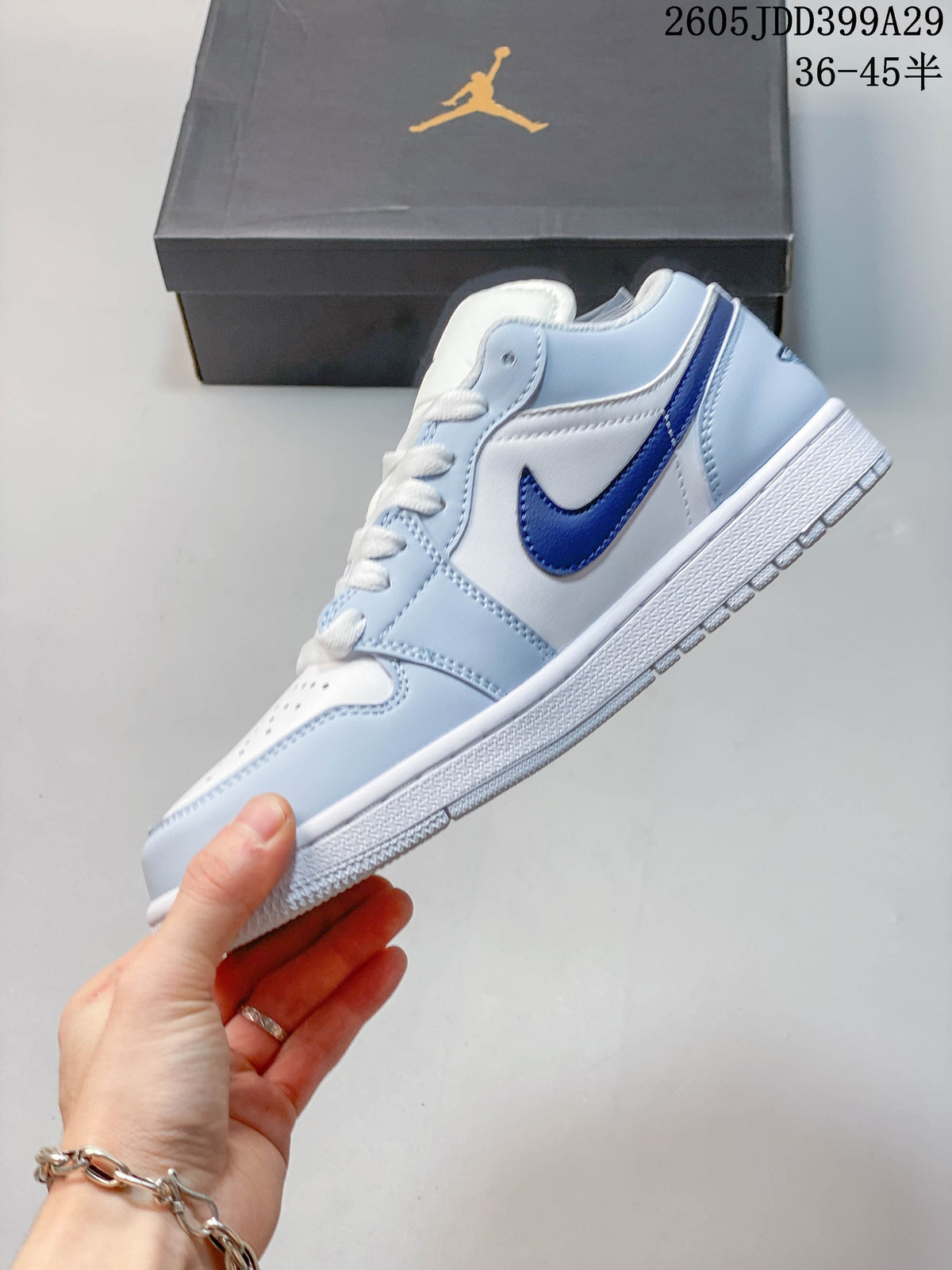 Side view of a low-top sneaker with light blue panels and a dark blue side logo
