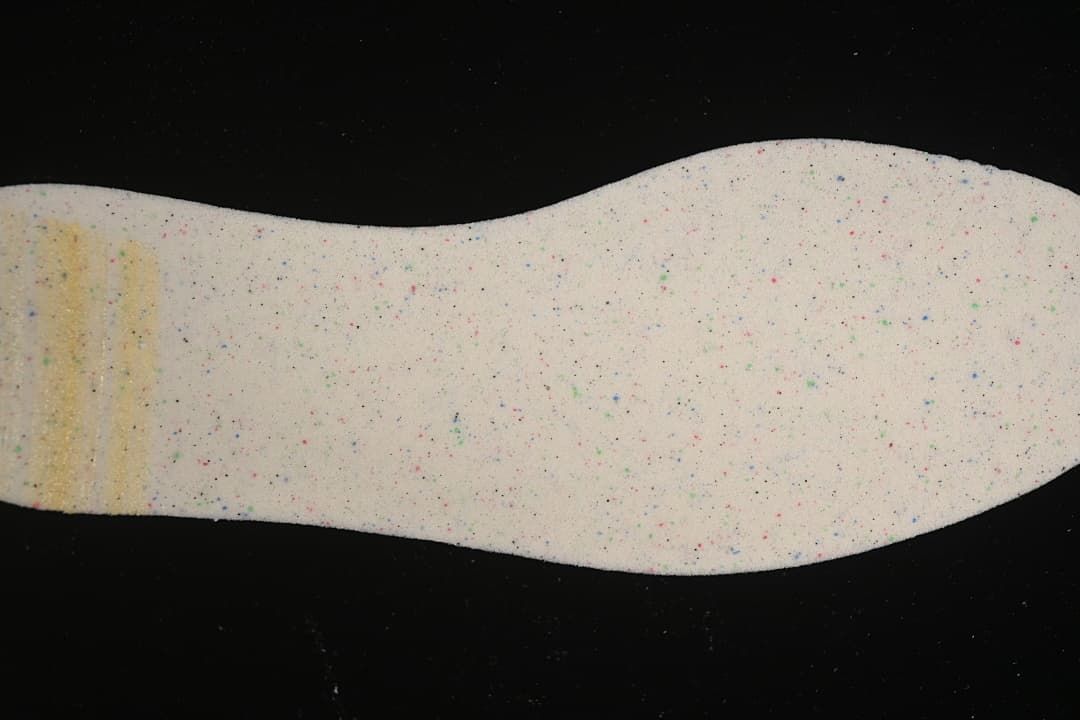 Close-up of a light-colored insole with small multicolor speckles.