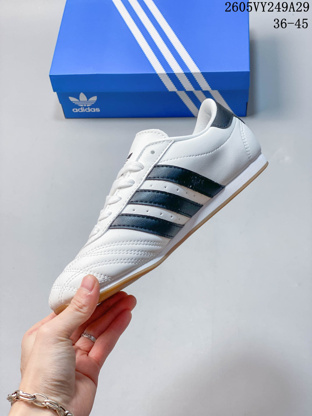 Side profile of a white adidas Taekwondo sneaker with dark stripes and gum-colored outsole