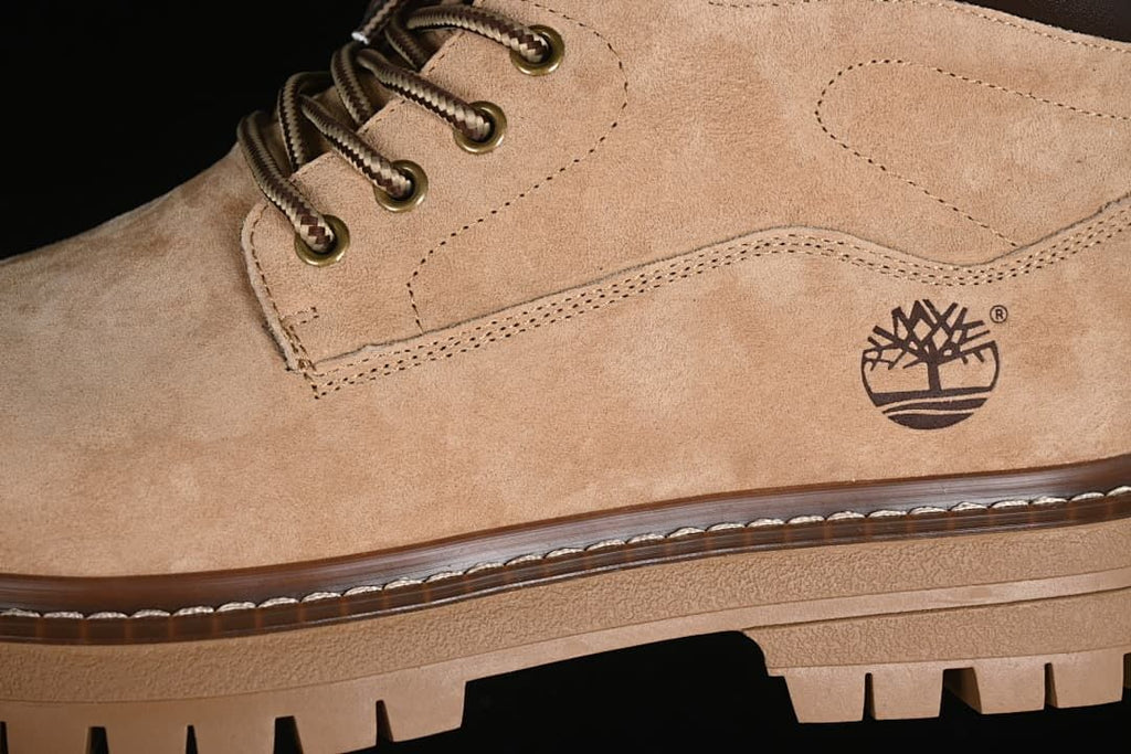 Close-up of the beige boot upper, laces, logo and sole stitching