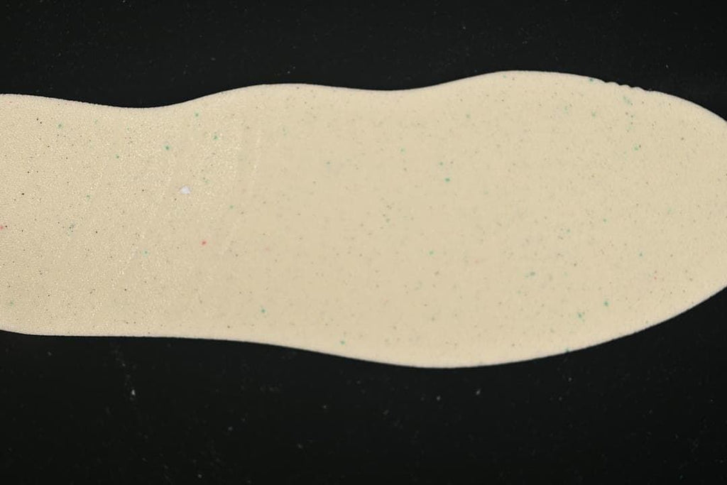 Light-colored shoe insole photographed against a dark background.