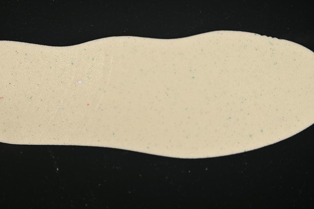 Light-colored shoe insole photographed against a dark background.