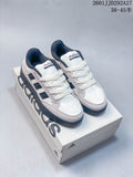 Pair of white Adidas Wcard Adv low-top sneakers with light gray overlays and dark stripes, shown on a shoebox