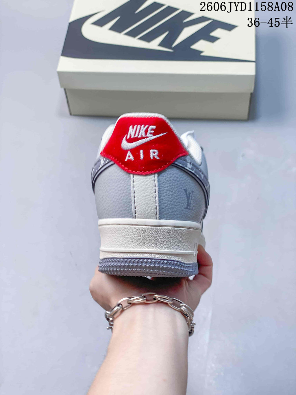 Rear view of a gray sneaker with a red heel tab and white midsole