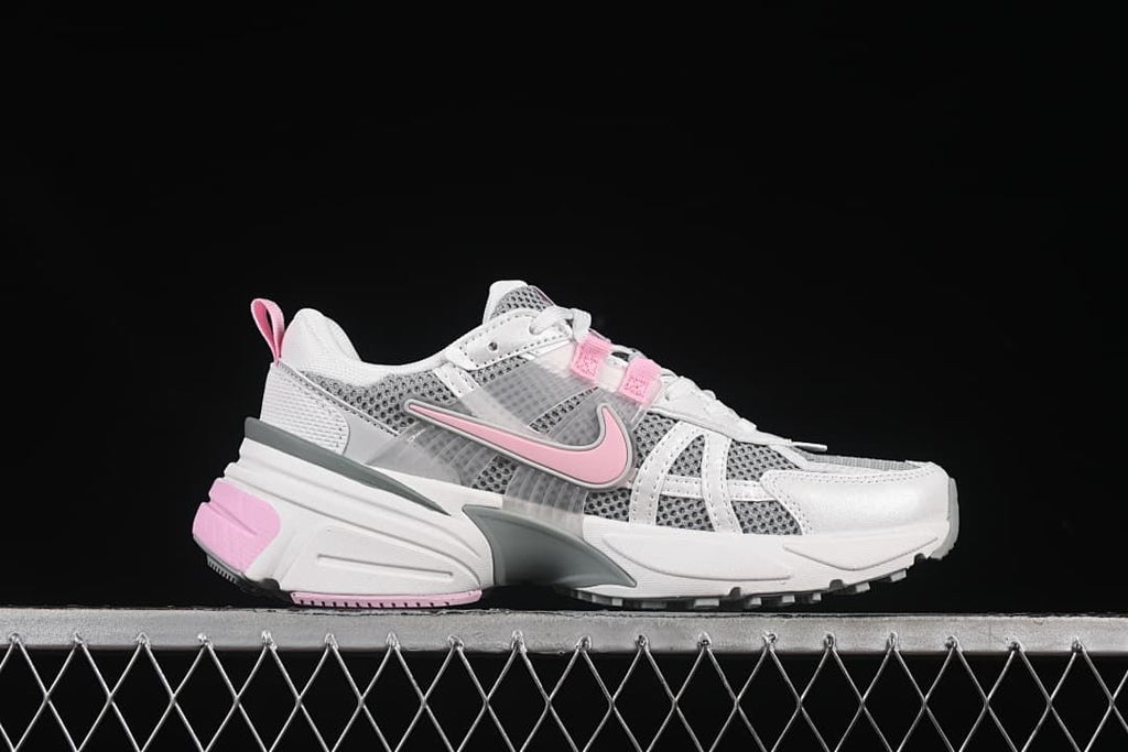 Side profile of a white and gray Nike V2K Run sneaker with pink accents