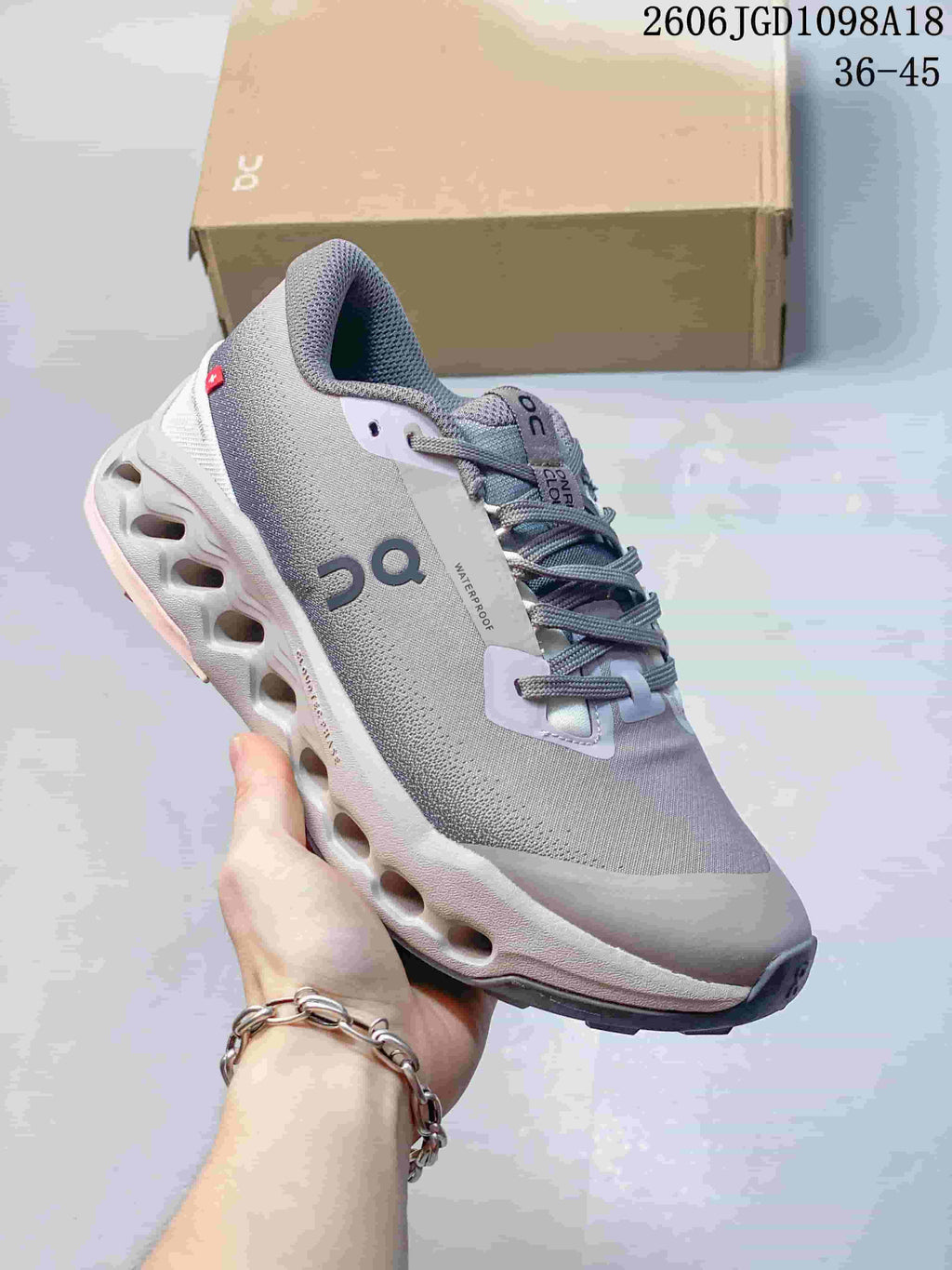 Angled side view of the gray and pale pink Cloudmonster 3 sneaker