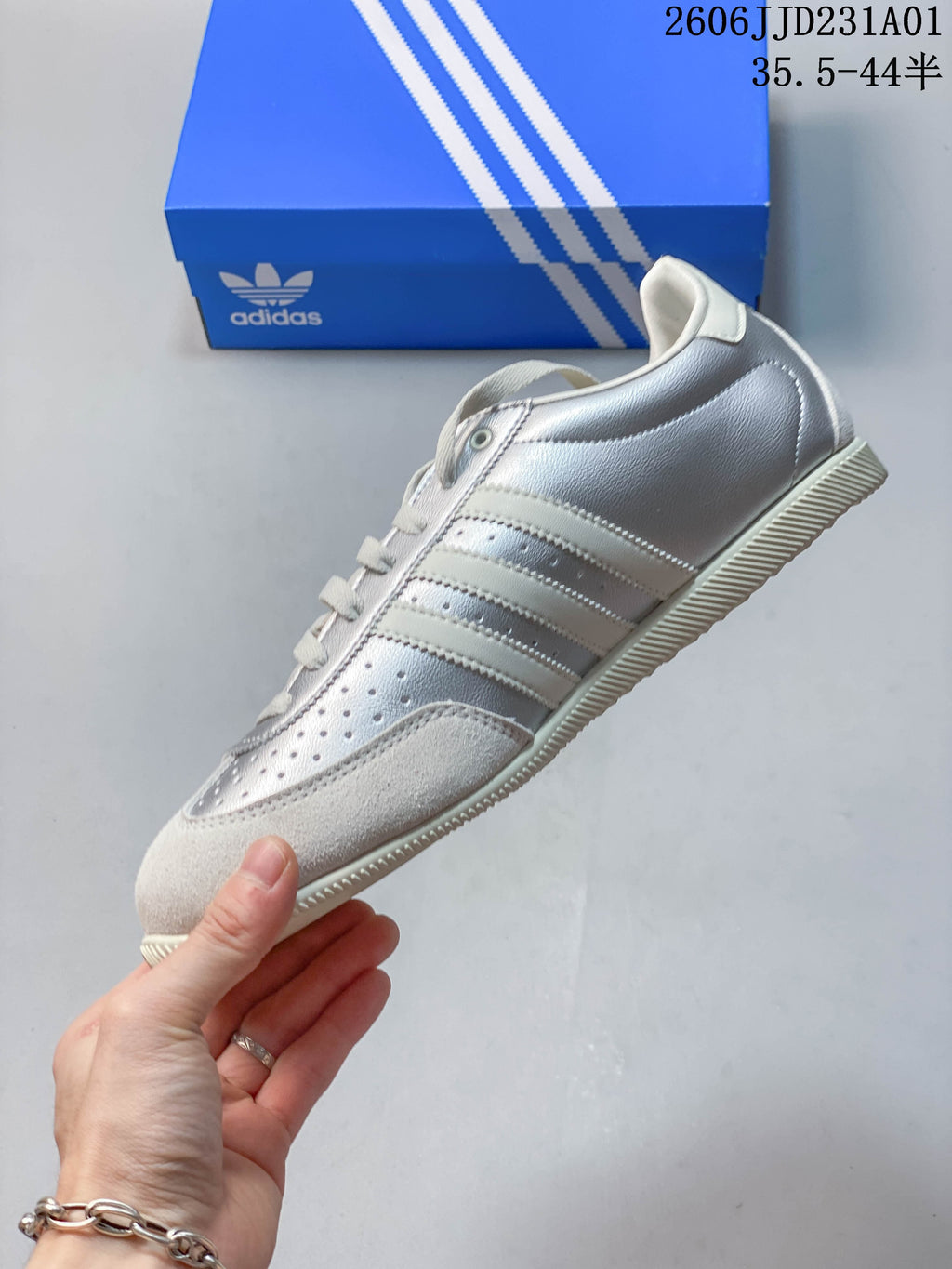 Side profile showing silver panels, three stripes, perforations, and off-white overlays