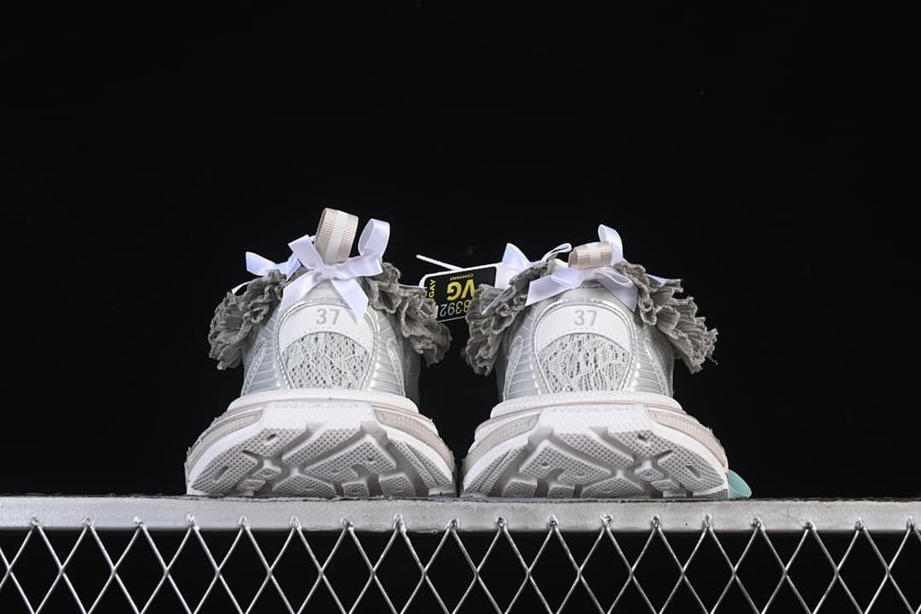 Rear view of both sneakers with textured outsole and ruffle trim