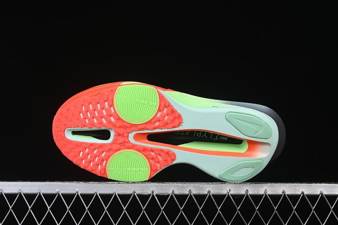 Outsole view showing bright-crimson and lime traction areas with central cutouts.