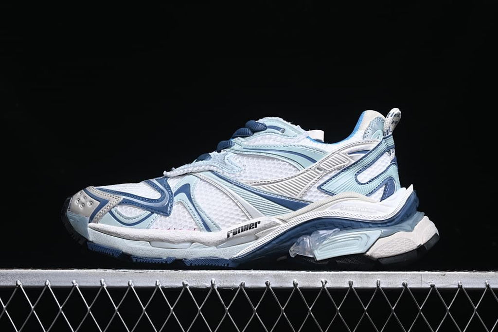Side view of a white and blue Balenciaga Runner-style sneaker against a dark background