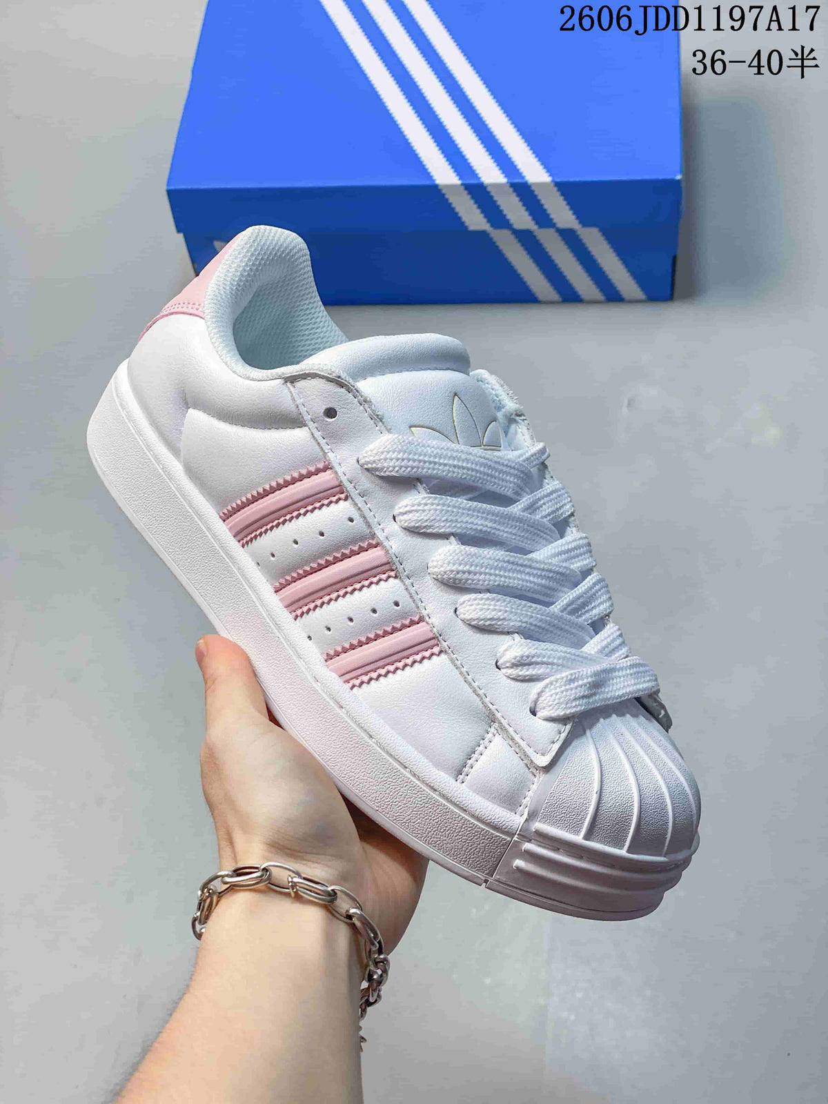 Angled side view of the white sneaker with pink accents and a shell toe.