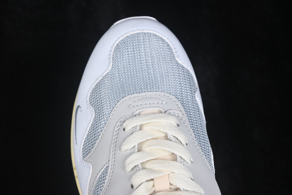 Close-up of the grey mesh toe box, stitched overlays and white laces.